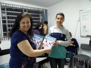 A Professora Coordenadora do Núcleo Pedagógico, Silvia Nogueira, da Diretoria de Ensino Leste 1 entrega um dos prêmios ao aluno Leonardo de Oliveira, do 1 o ano do Ensino Médio da E.E. Profª Irene Branco da Silva.